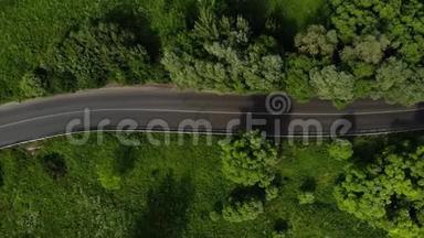 绿色森林中的道路空中镜头，几辆汽车在高速公路上行驶。 汽车在绿色的柏油路上行驶
